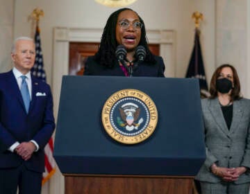 Judge Ketanji Brown Jackson speaks from a podium, with President Biden to her right and Vice President Harris to her left