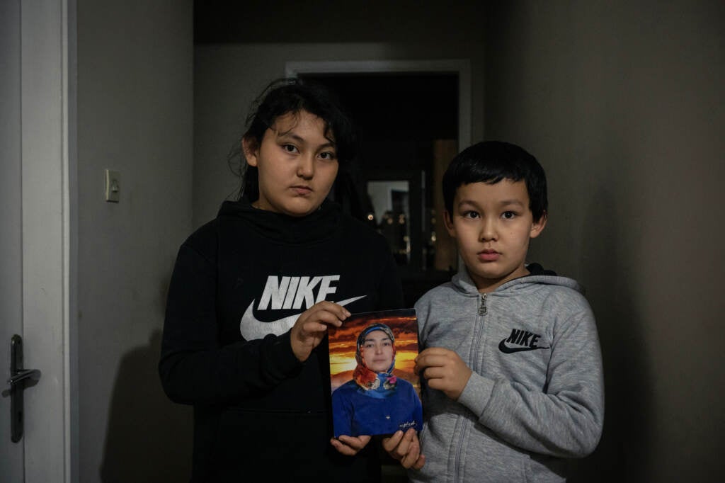 Aysu and Lutfulla Kuça hold up a photo of their mother