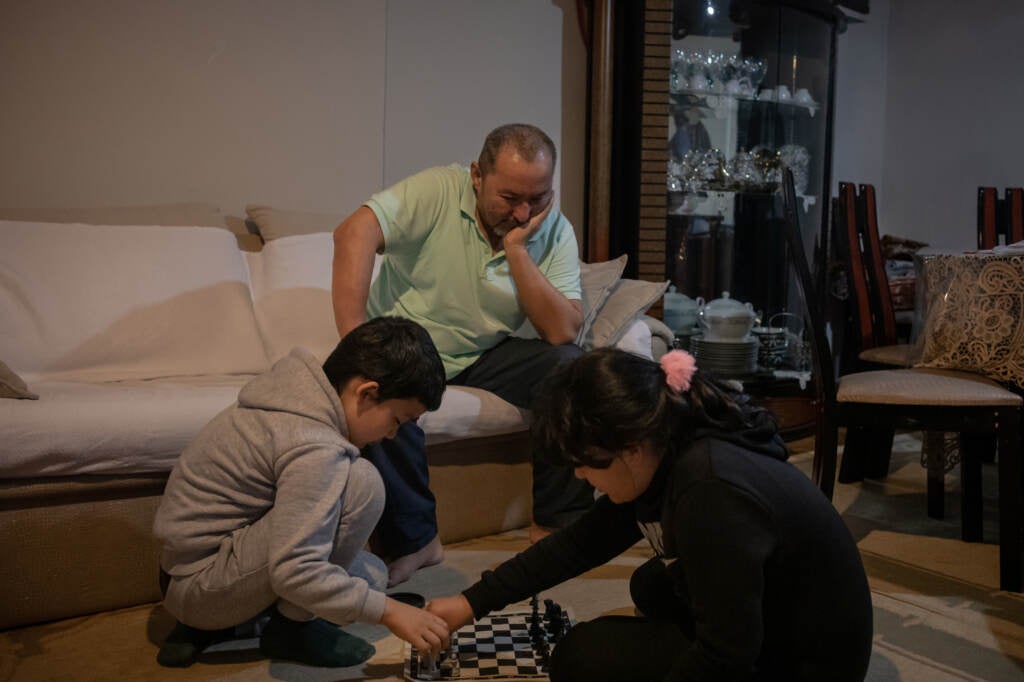 Abdullatif Kuçar watches his two children play chess in the living room