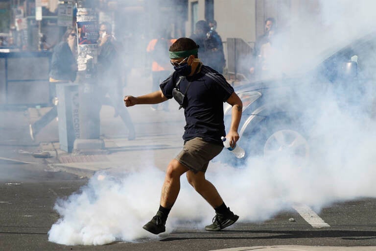 A protester kicks a tear gas canister fired by police as protests continue Sunday, May 31, 2020, in Philadelphia over the death of George Floyd. Floyd died May 25 after he was pinned at the neck by a Minneapolis police officer. (AP Photo/Matt Rourke)