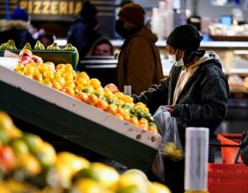 A shopper wearing a face mask selects fruit at the Reading Terminal Market
