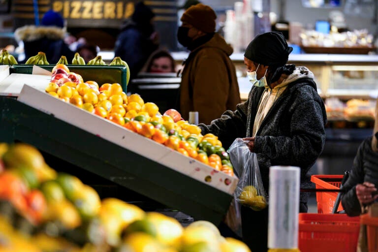 A shopper wearing a face mask selects fruit at the Reading Terminal Market