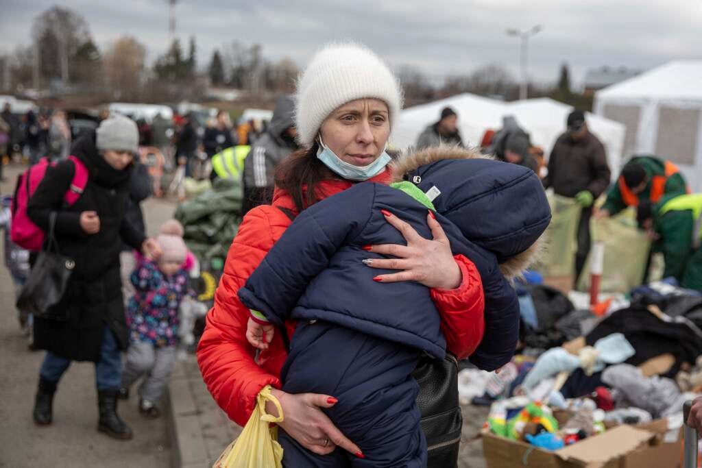 A woman carries her child as she arrives at the Medyka border crossing