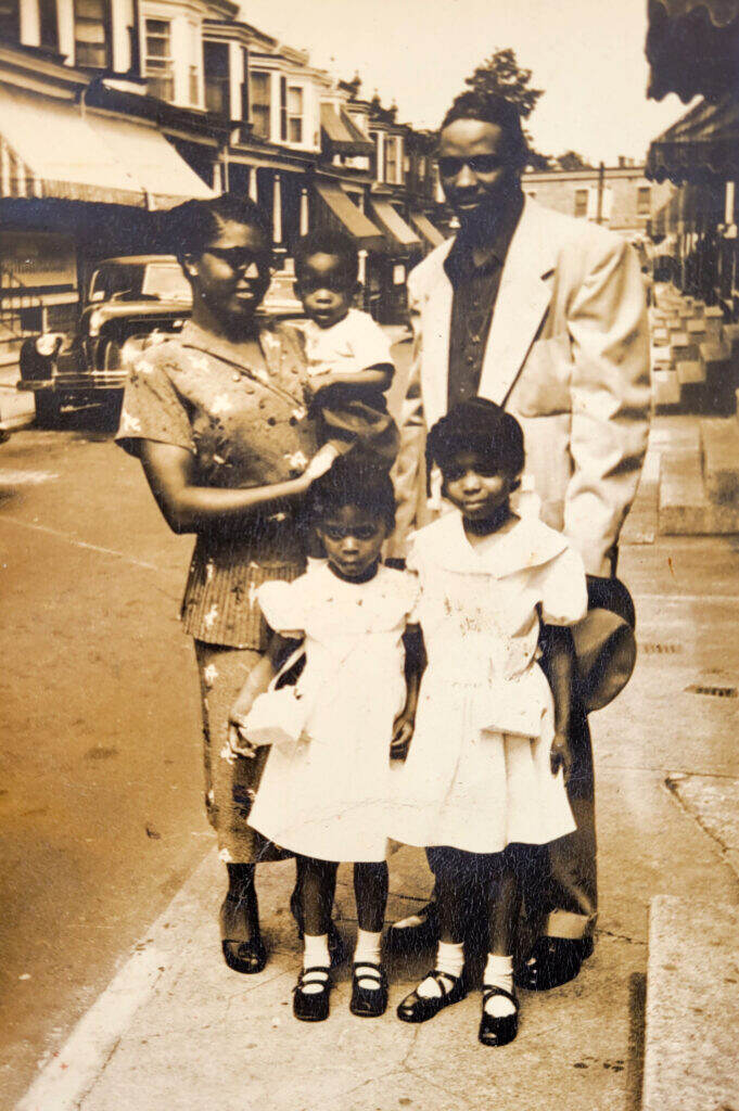 A Black family poses near their home