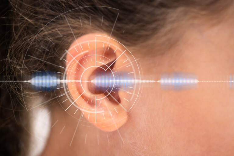 A human ear overlaid with a graphic representing hearing and sound