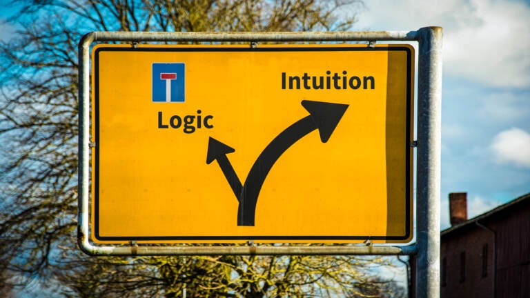 A yellow street sign with arrows directing towards logic and intuition