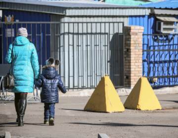 People walk past anti-tank barriers in the Donetsk region town of Avdiivka