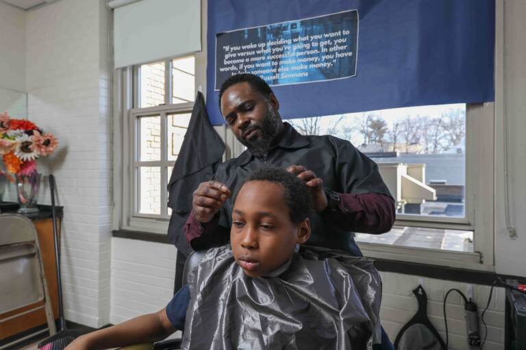 Terrance Newton cuts the hair of Warner student Elijah Jackson in March 2020, days before the pandemic shut down schools and his school barbershop. (Saquan Stimpson for WHYY)