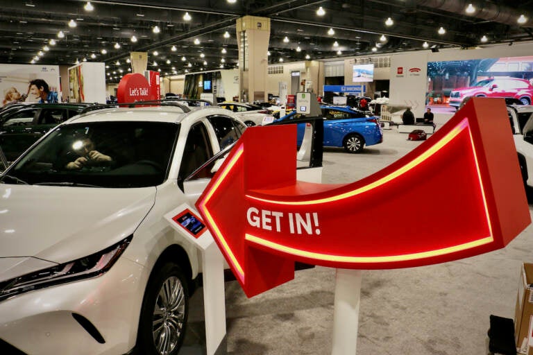 A sign invites visitors to sit in the cars at the Philadelphia Auto Show. (Emma Lee/WHYY)