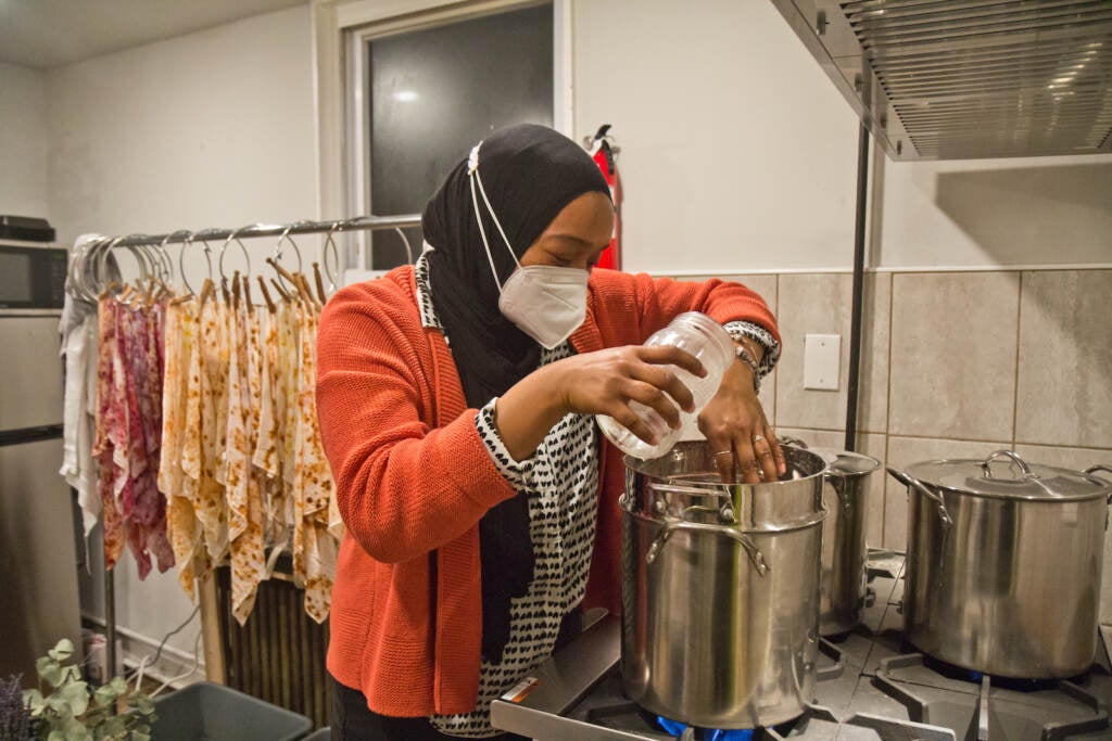 Modest Transitions owner, Melanie Hasan, places bundled fabrics in a steam bath