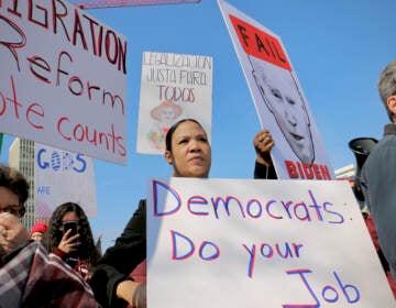 Immigration reform activists wait for President Biden across the street from the Hilton Philadelphia, where he addressed the House Democratic Caucus. (Emma Lee/WHYY)