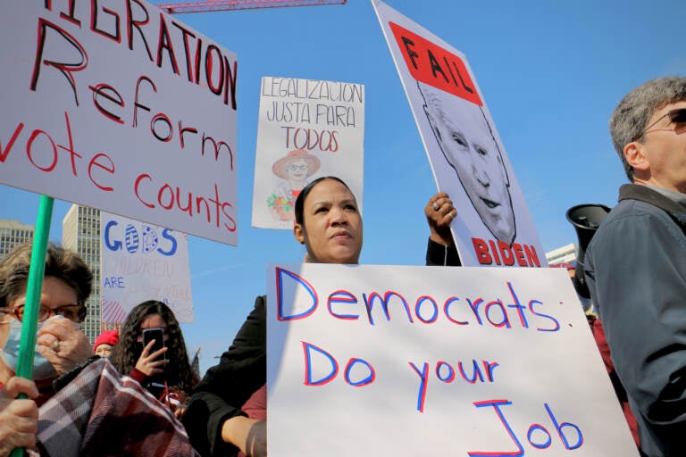 Immigration reform activists wait for President Biden across the street from the Hilton Philadelphia, where he addressed the House Democratic Caucus. (Emma Lee/WHYY)