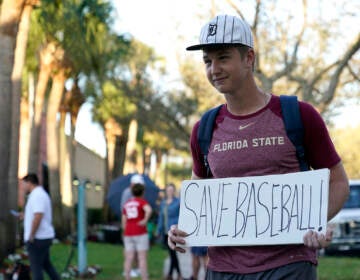 Baseball fan Noah McMurrain of Boynton Beach, Fla., stands outside Roger Dean Stadium as Major League Baseball negotiations continue in an attempt to reach an agreement to salvage a March 31 start to the regular season, Monday, Feb. 28, 2022, in Jupiter, Fla. (AP Photo/Lynne Sladky)