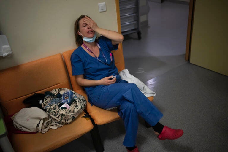 FILE - Nurse Marie-Laure Satta pauses during her New Year's Eve shift in the COVID-19 intensive care unit at the la Timone hospital in Marseille, southern France, Friday, Dec. 31, 2021. The official global death toll from COVID-19 is on the verge of eclipsing 6 million — underscoring that the pandemic, now in its third year, is far from over. (AP Photo/Daniel Cole, File)