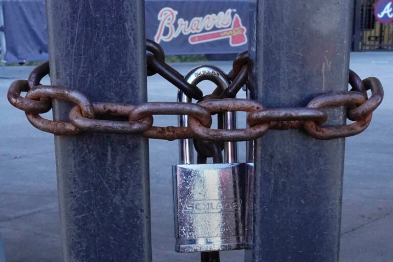 Locked gates are shown at Truist Park, home of the Atlanta Braves baseball team, Wednesday, March 2, 2022, in Atlanta. With owners and players unable to agree on a labor contract to replace the collective bargaining agreement that expired Dec. 1, baseball commissioner Rob Manfred followed through with his threat on Tuesday and canceled the first two series for each of the 30 major league teams. (AP Photo/John Bazemore)