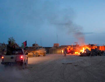 In this April 28, 2011, photo, an Afghan National Army pickup truck passes parked U.S. armored military vehicles, as smoke rises from a fire in a trash burn pit at Forward Operating Base Caferetta Nawzad, Helmand province south of Kabul, Afghanistan. The House just passed legislation that may dramatically boost health care services and disability benefits for veterans exposed to burn pits in Iraq and Afghanistan. (AP Photo/Simon Klingert, File)