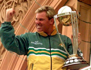 File photo: Australia's Shane Warne clenches his fist as he holds the Cricket World Cup Trophy on the team balcony at Lords after Australia defeated Pakistan by 8 wickets in the final of the Cricket World Cup, in London Sunday, June 20, 1999. Shane Warne, one of the greatest cricket players in history, has died. He was 52. (AP Photo/Rui Vieira, File)