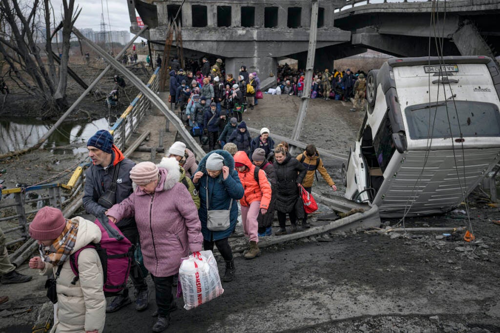 People cross on an improvised path under a bridge that was destroyed by a Russian airstrike, while fleeing the town of Irpin, Ukraine, Saturday, March 5, 2022. What looked like a breakthrough cease-fire to evacuate residents from two cities in Ukraine quickly fell apart Saturday as Ukrainian officials said shelling had halted the work to remove civilians hours after Russia announced the deal.