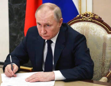 Russian President Vladimir Putin sits at a table