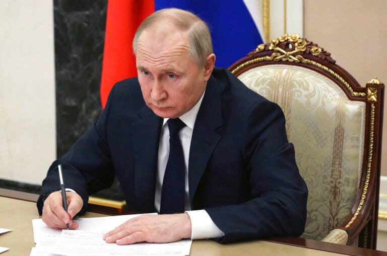 Russian President Vladimir Putin sits at a table
