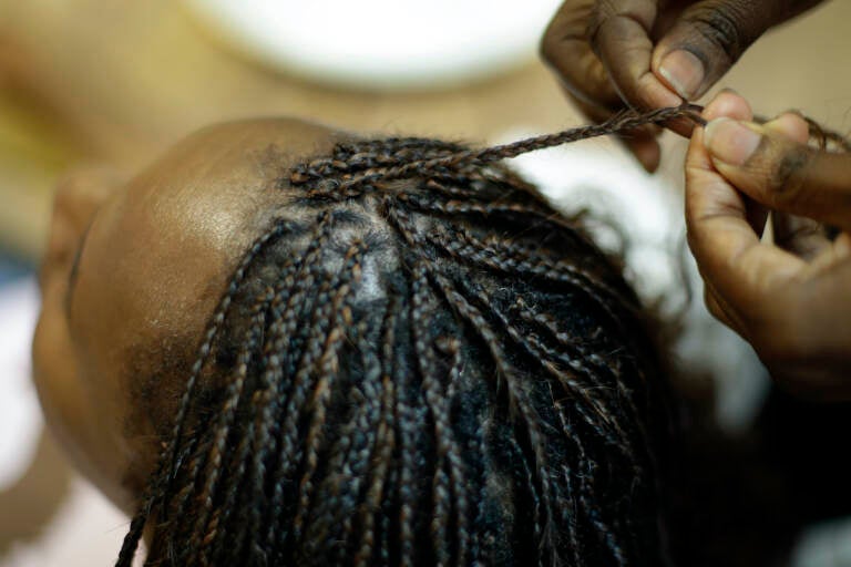 Shelly Smith braids hair for Bridget Dunmore at her salon, Braid Heaven Tuesday, Jan. 28, 2020 in Kansas City, Kan. (AP Photo/Charlie Riedel)