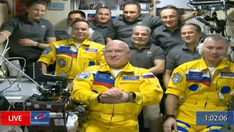 In this frame grab from video provided by Roscosmos, Russian cosmonauts Sergey Korsakov, Oleg Artemyev and Denis Matveyev are seen during a welcome ceremony after arriving at the International Space Station, Friday, March 18, 2022, the first new faces in space since the start of Russia’s war in Ukraine. The crew emerged from the Soyuz capsule wearing yellow flight suits with blue stripes, the colors of the Ukrainian flag