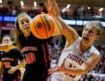 Princeton forward Ellie Mitchell (00) and Indiana forward Aleksa Gulbe (10) reach for the ball as they go for a long rebound in the second half of a college basketball game in the second round of the NCAA tournament in Bloomington, Ind., Monday, March 21, 2022. Indiana defeated Princeton 56-55. (AP Photo/Michael Conroy)