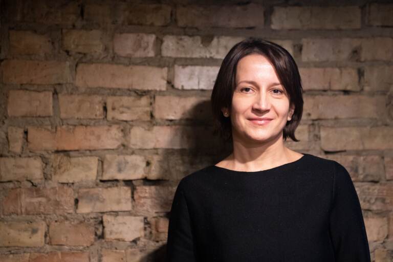 Ukrainian playwright Natal'ya Vorozhbit poses in a black shirt, in front of a brick wall.