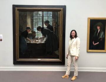Dr. Anna O. Marley stands in front of a painting hung on a wall at PAFA.
