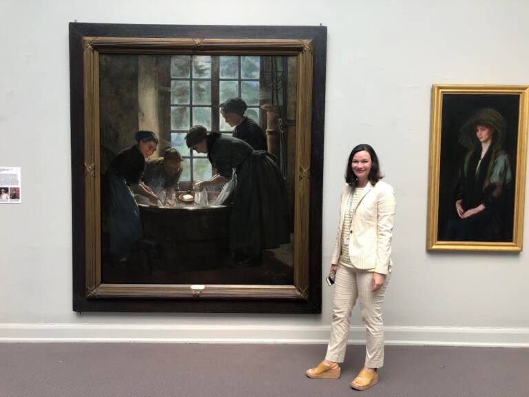 Dr. Anna O. Marley stands in front of a painting hung on a wall at PAFA.