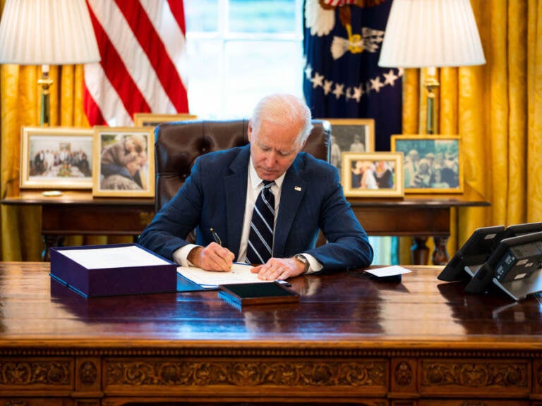 Biden signs a document at his desk
