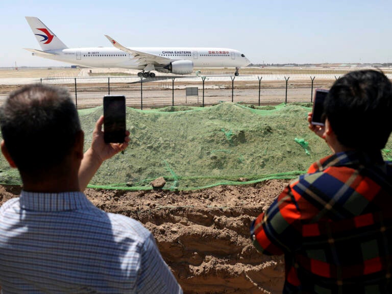 Residents watch as a China Eastern passenger jet prepares to take off