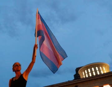 Cole Ramsey, 39, of South Linden, Ohio, holds a Transgender Pride Flag in front of the Ohio Statehouse in Columbus to protest the passing of legislation against trans women playing sports in high school and college. (Stephen Zenner/SOPA Images/LightRocket via Getty Images)