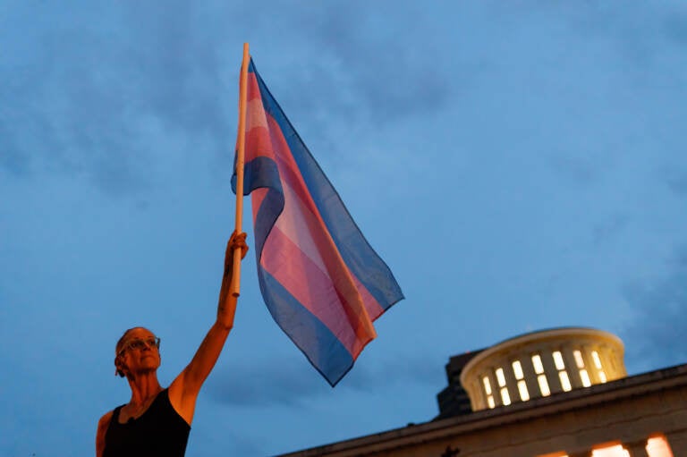 Cole Ramsey, 39, of South Linden, Ohio, holds a Transgender Pride Flag in front of the Ohio Statehouse in Columbus to protest the passing of legislation against trans women playing sports in high school and college. (Stephen Zenner/SOPA Images/LightRocket via Getty Images)