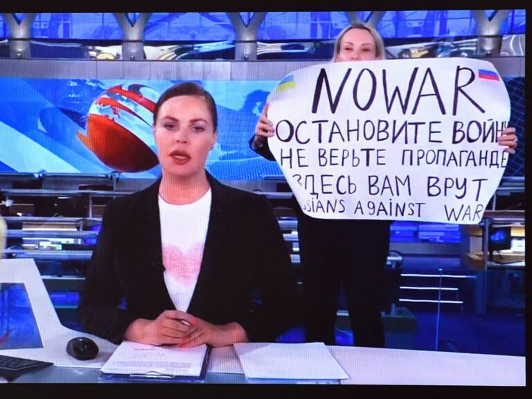 A dissenting Channel One employee holding a poster reading as 'No War'