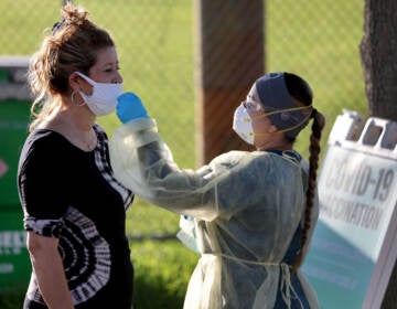 A nurse swabs a woman's nose for a COVID-19 test.