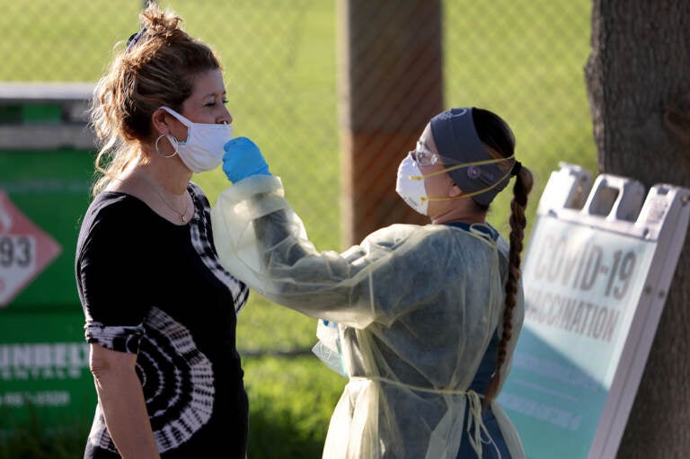 A nurse swabs a woman's nose for a COVID-19 test.