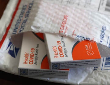 In this photo illustration, free iHealth COVID-19 antigen rapid tests from the federal government sit on a U.S. Postal Service envelope after being delivered on Feb. 4, 2022. (Justin Sullivan/Getty Images)