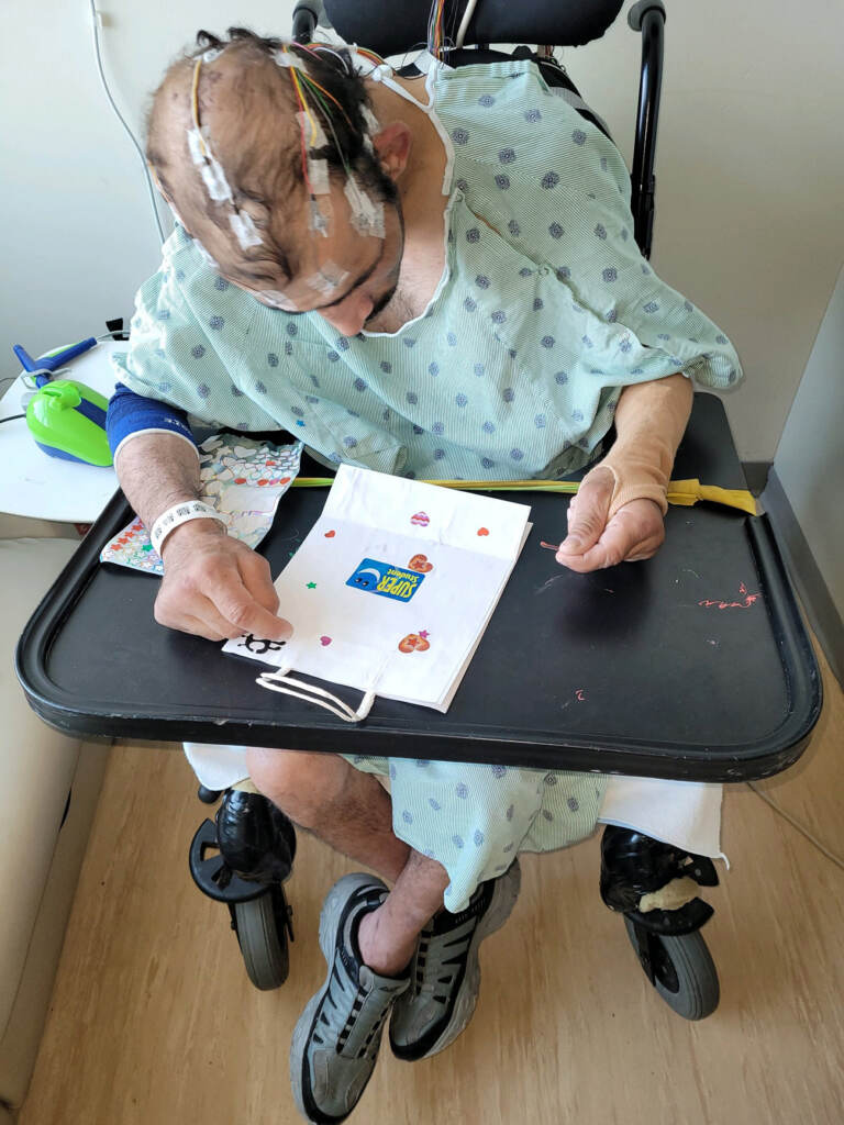 Steven Abi Richa in a wheelchair in a hospital putting stickers on a paper bag