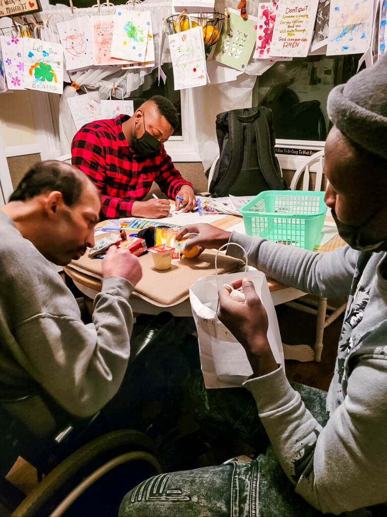 Steven Abi Richa at a table working with two other volunteers to fill and decorate "Steven's Bags"