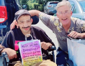 Steven Abi Richa (left) holding a decorated paper bag filled with household items next to Chris Batton (right)