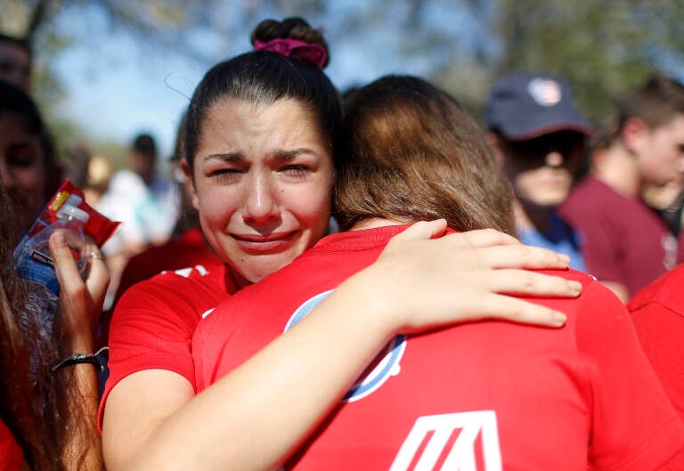 File photo: A student mourns the loss of her friend during a community vigil at Pine Trails Park, Thursday, Feb. 15, 2018, in Parkland, Fla., for the victims of the shooting at Marjory Stoneman Douglas High School. She is crying as she embraces someone.