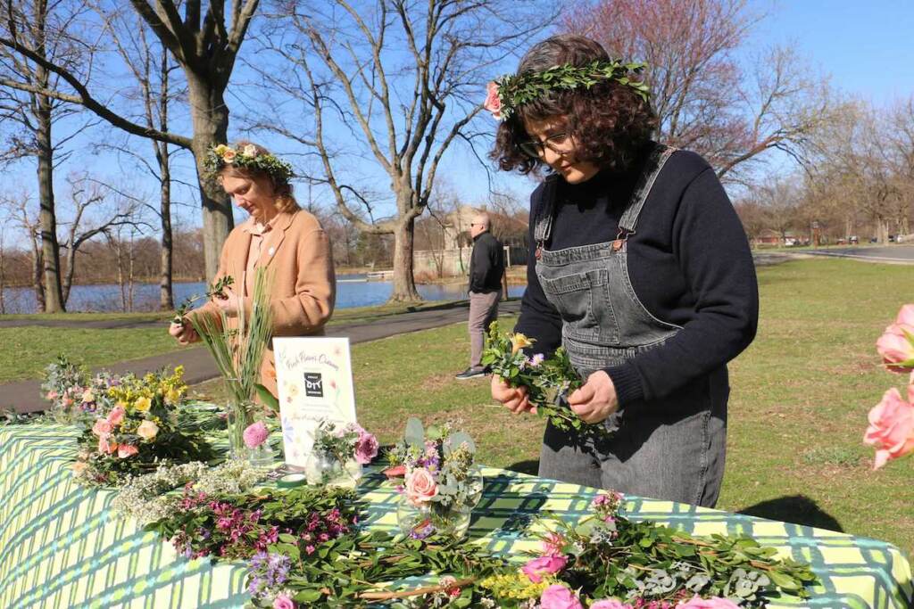Jackie Small (left) and Miriam Singer of Philly DIY Wedding weave flower crowns during a preview of the Philadelphia Flower Show at FDR Park. (Emma Lee/WHYY)