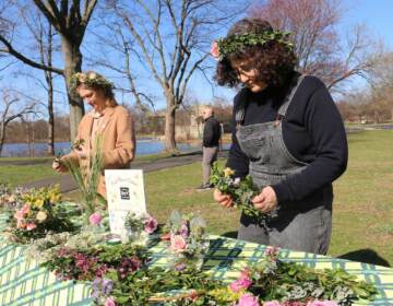 Jackie Small (left) and Miriam Singer of Philly DIY Wedding weave flower crowns during a preview of the Philadelphia Flower Show at FDR Park. (Emma Lee/WHYY)