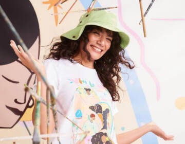 Manuela Gillén gestures while smiling in front of a mural