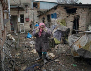 A woman is overwhelmed by emotion in the backyard of a house damaged by a Russian airstrike