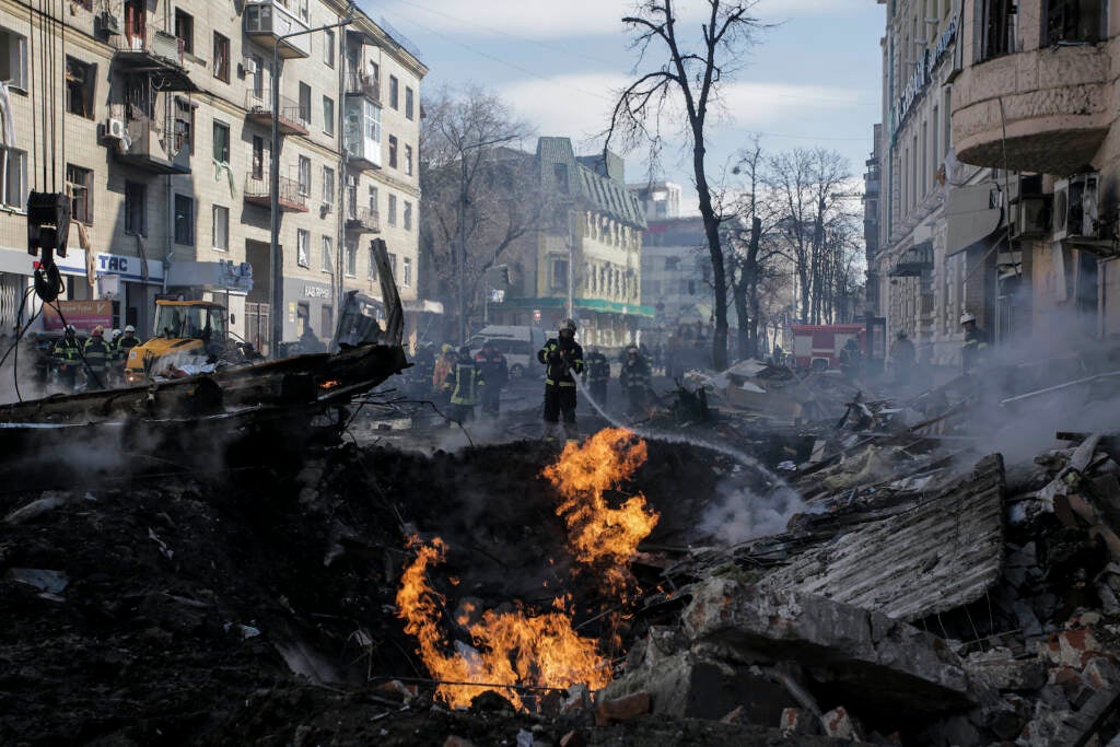 Firefighters extinguish flames outside an apartment house after a Russian rocket attack in Kharkiv,