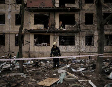 A Ukrainian firefighter walks outside a destroyed building after it was hit by artillery shelling in Kyiv