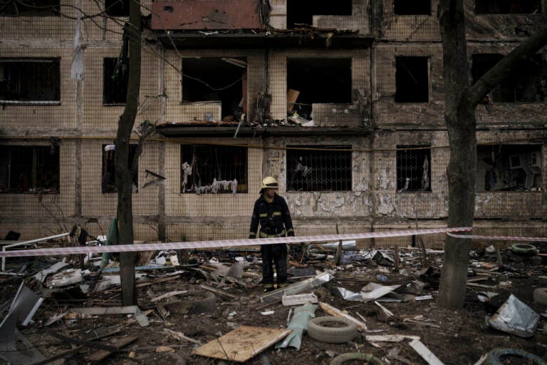 A Ukrainian firefighter walks outside a destroyed building after it was hit by artillery shelling in Kyiv