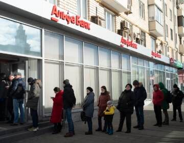 People stand in line to withdraw money from an ATM of Alfa Bank in Moscow